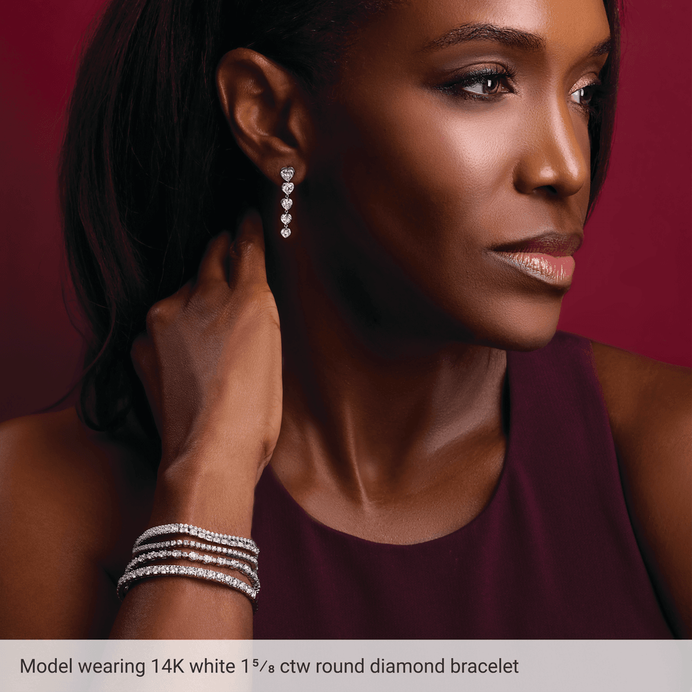 Woman wearing diamond earrings and bracelet against a red background
