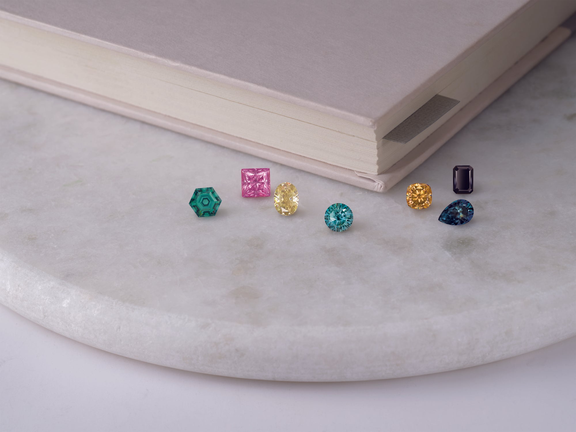 Colorful gemstone earrings on a marble surface with a book in the background